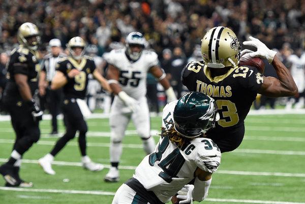 Football player Thomas catches pass against Eagles defender.