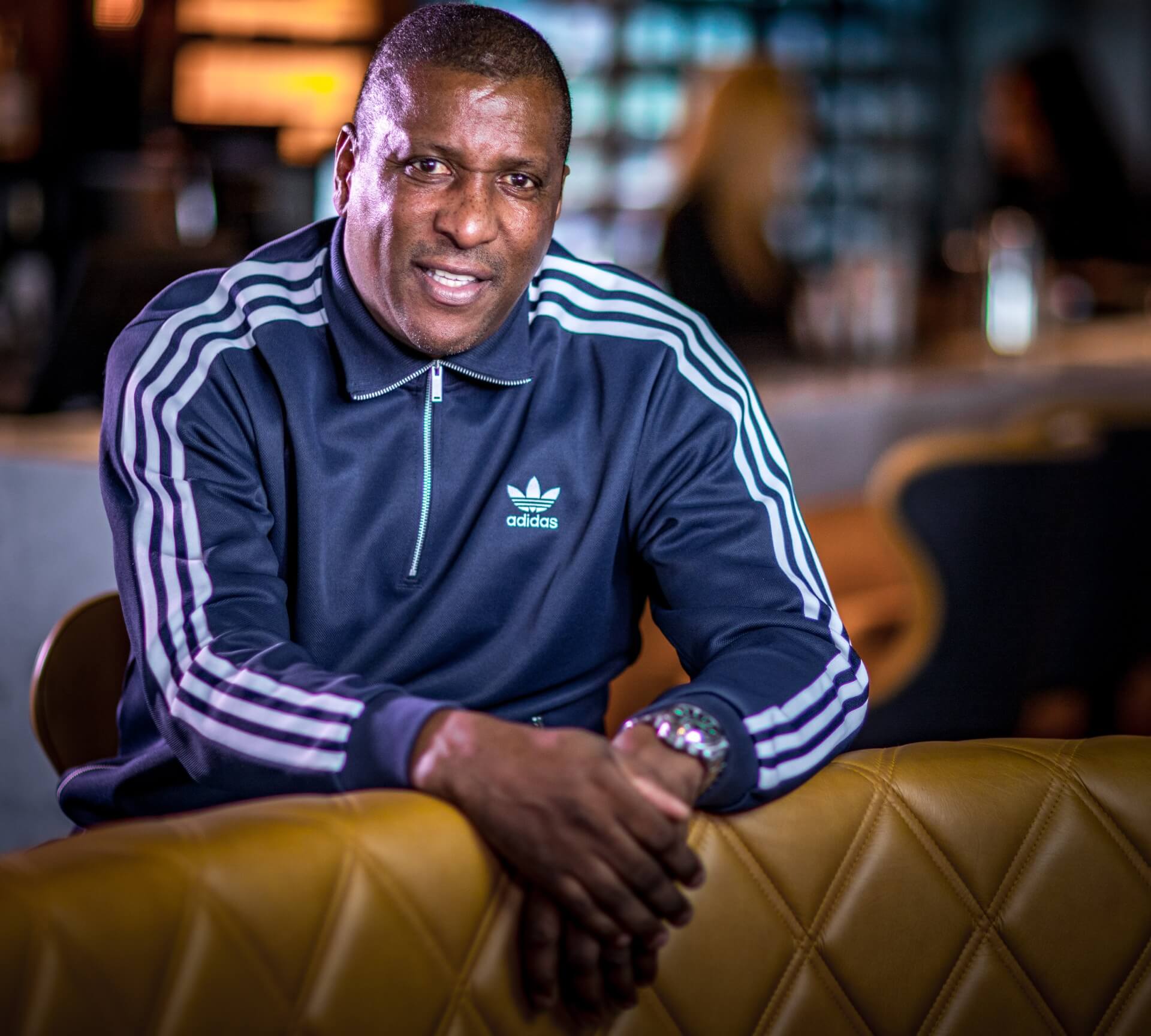 Person in a blue Adidas track jacket in a bar setting.