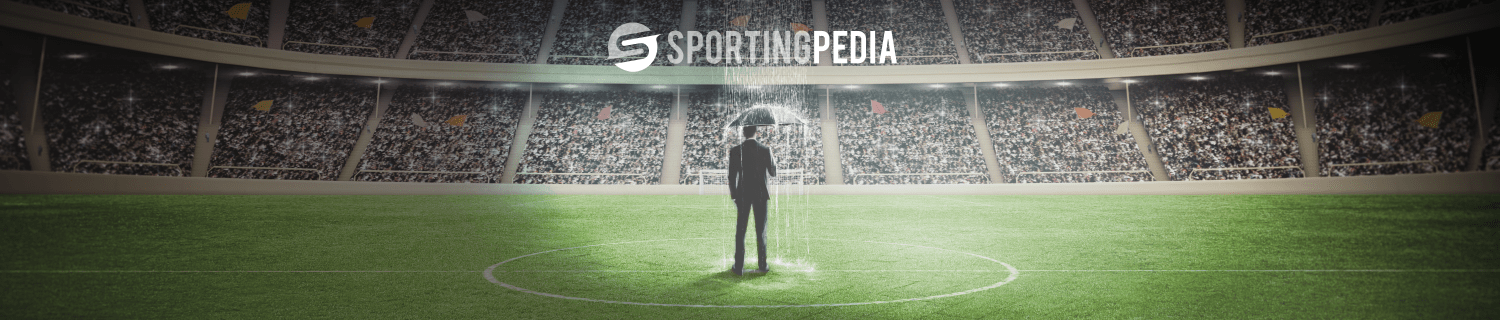 Man with umbrella on football field surrounded by crowd.