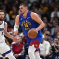 Nikola Jokic dribbles the ball with Domantas Sabonis watching