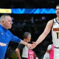 Former Denver Nuggets coach Michael Malone clapping hands with Nikola Jokic