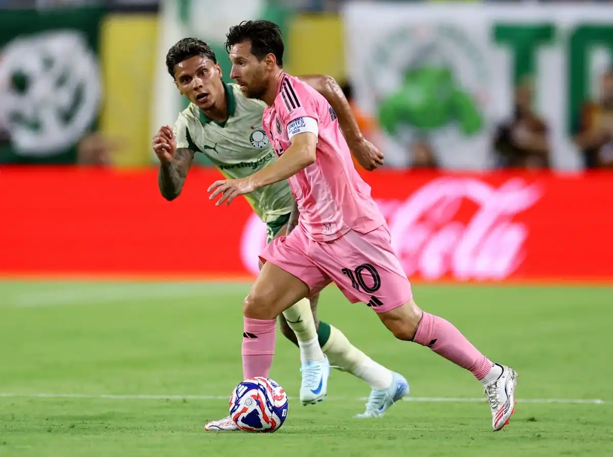 Leo Messi dribbles the ball, chased by a Palmeiras player