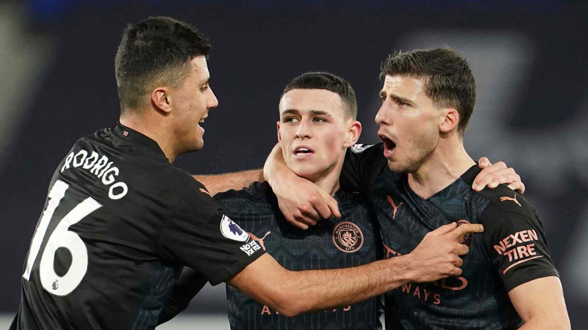 Rodri, Phil Foden, and Ruben Dias of Manchester City hugging one another