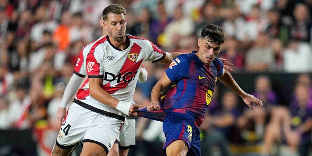 Pedri having his shirt pulled by a Rayo Vallecano player