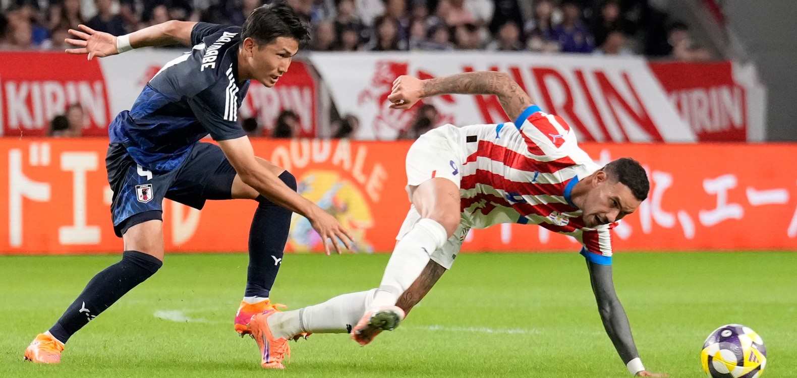 Players from Japan and Paraguay in a battle for the ball