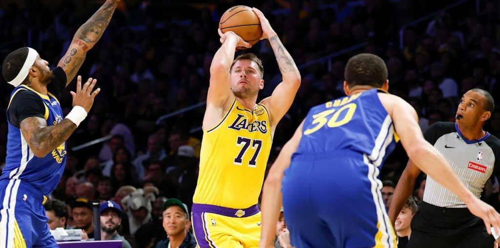 Luka Doncic shoots guarded by Gary Payton II and Steph Curry