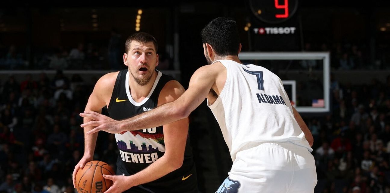 Nikola Jokic holding the ball, guarded by Santi Aldama