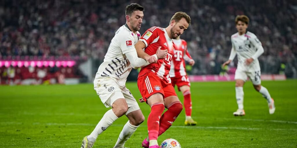 Mainz player trying to take the ball from Harry Kane