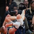 Nikola Jokic holding his knee after getting injured in the game against Miami Heat