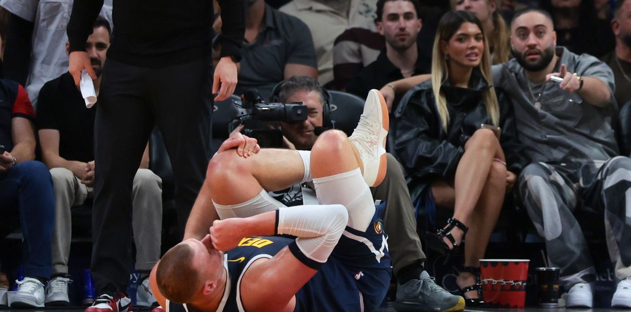 Nikola Jokic holding his knee after getting injured in the game against Miami Heat