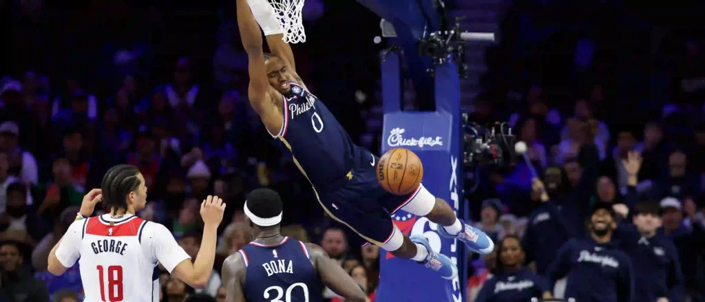 Tyrese Maxey hanging on the basket after a dunk