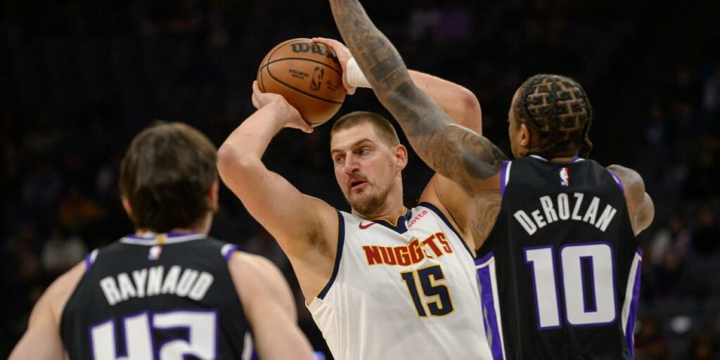 Nikola Jokic looking for a pass while guarded by DeMar DeRozan and Maxime Raynaud