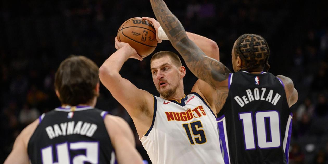 Nikola Jokic looking for a pass while guarded by DeMar DeRozan and Maxime Raynaud