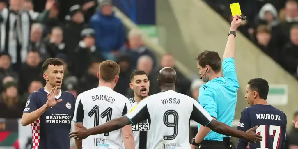 Referee brandishes yellow card in the match between Newcastle and PSV