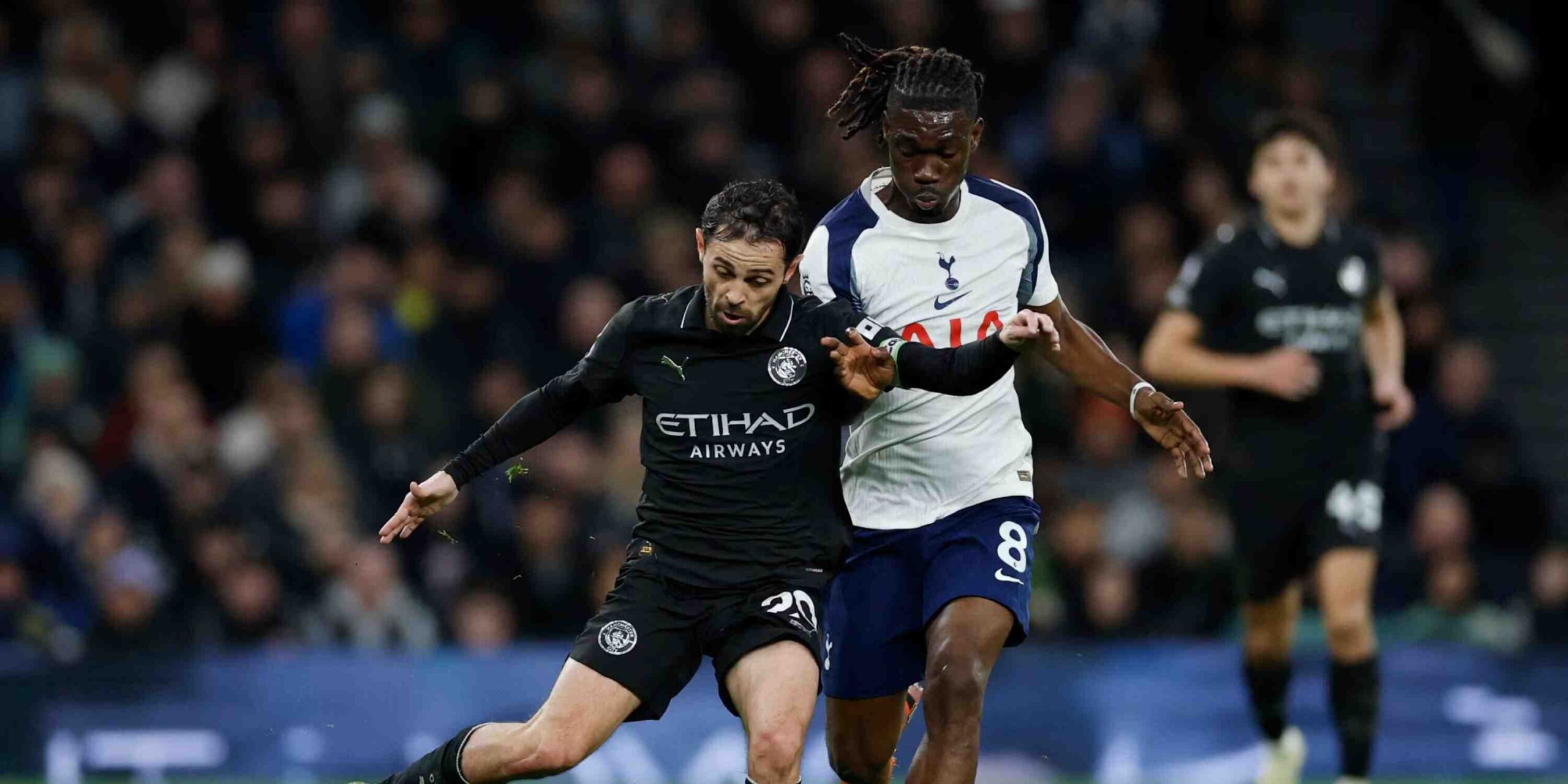 Bernardo Silva trying to pass the ball under pressure from a Tottenham player