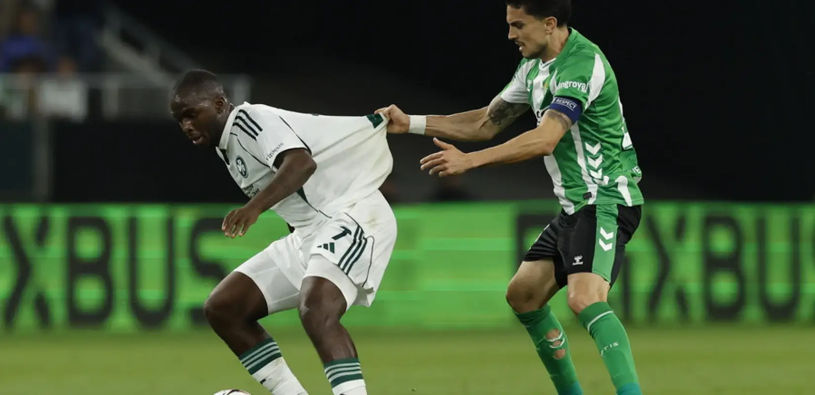Panathinaikos player protecting the ball from a Betis opponent