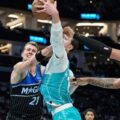 Moritz Wagner and Paolo Banchero trying to prevent Charlotte Hornets player from scoring