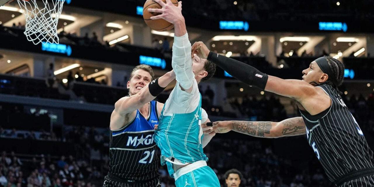 Moritz Wagner and Paolo Banchero trying to prevent Charlotte Hornets player from scoring