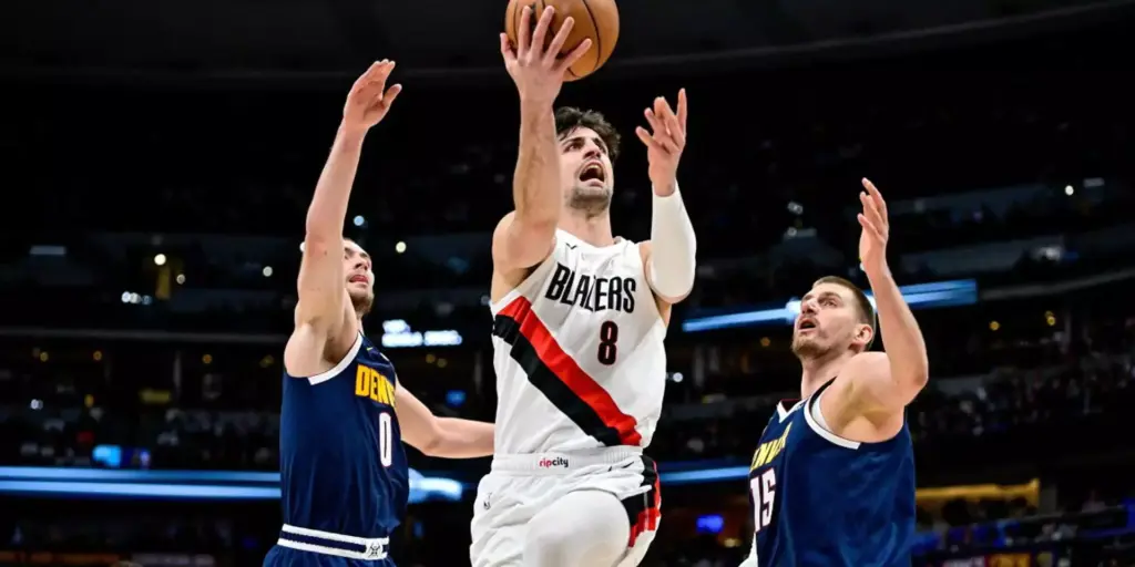 Deni Avdija trying to score in Denver's basket despite Nikola Jokic and Christian Braun's defense