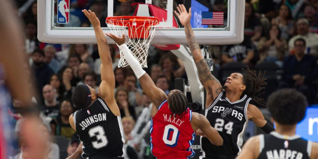 Keldon Johnson, Tyrese Maxey, and Victor Wembanyama jumping for a rebounded ball