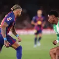 Raphinha trying to dribble past a Betis player