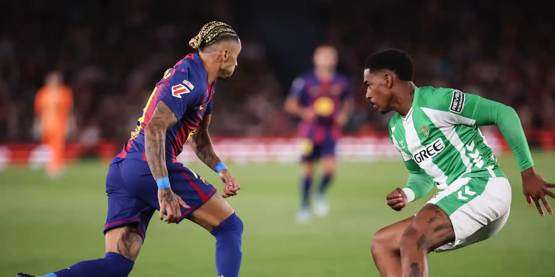 Raphinha trying to dribble past a Betis player