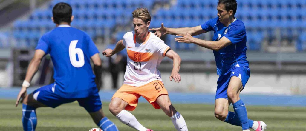 Frenkie de Jong dribbles the ball, surrounded by couple of Uzbekistan opponents