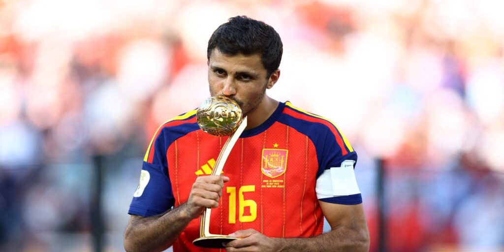Rodri holding the World Cup Golden Ball trophy